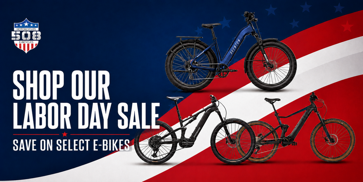 Promotional banner for a Labor Day sale featuring three electric bicycles against a stylized American flag background with the text 'SHOP OUR LABOR DAY SALE' and 'SAVE ON SELECT E-BIKES'.