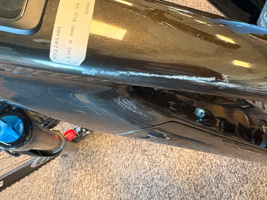 Close-up of a glossy black bicycle frame with a white inventory label reading '952241384 LEVO 4 PRO BLK S4 80%'.